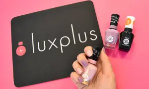 Få till perfekt shellac hemma med Sally Hansens gel-lack. En hand med målade naglar håller en ljusrosa flaska, bredvid två andra flaskor och en Luxplus-logga.