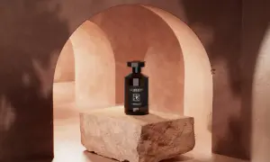 En mörk flaska med parfymen Le Couvent står på en sten.