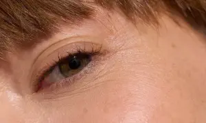 Närbild på ett öga med brun iris och mörka ögonfransar. Huden är tunn och visar fina linjer runt ögat.