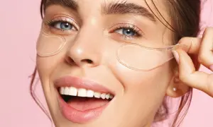 En kvinna ler glatt med eye patches under ögonen. Se hur eye patches sitta för bästa resultat.