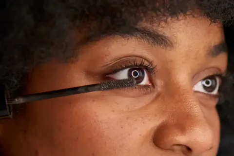 När du vill ta bort vattenfast mascara, använd en mild rengöring. Bilden visar en person som applicerar mascara.