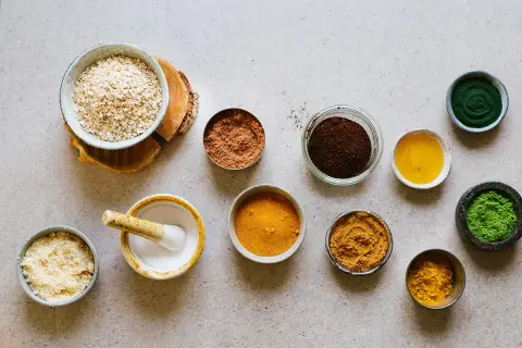 Ingredienser för hemmagjord peeling socker: havregryn, kakaopulver, kaffesump, gurkmeja, matcha och olja.