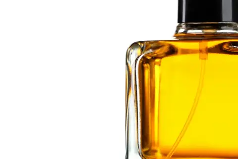 En flaska med gyllene parfym, som lovar en varm och sensuell amber doft.