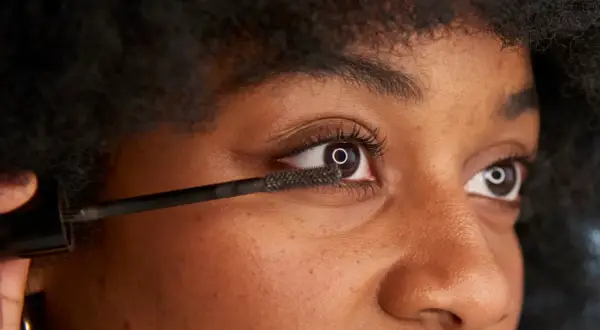 När du vill ta bort vattenfast mascara, använd en mild rengöring. Bilden visar en person som applicerar mascara.