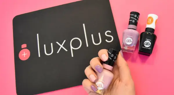 Få till perfekt shellac hemma med Sally Hansens gel-lack. En hand med målade naglar håller en ljusrosa flaska, bredvid två andra flaskor och en Luxplus-logga.