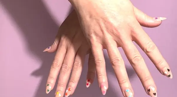 Händer med naglar dekorerade med färgglada hjärtan, en hyllning till pride.