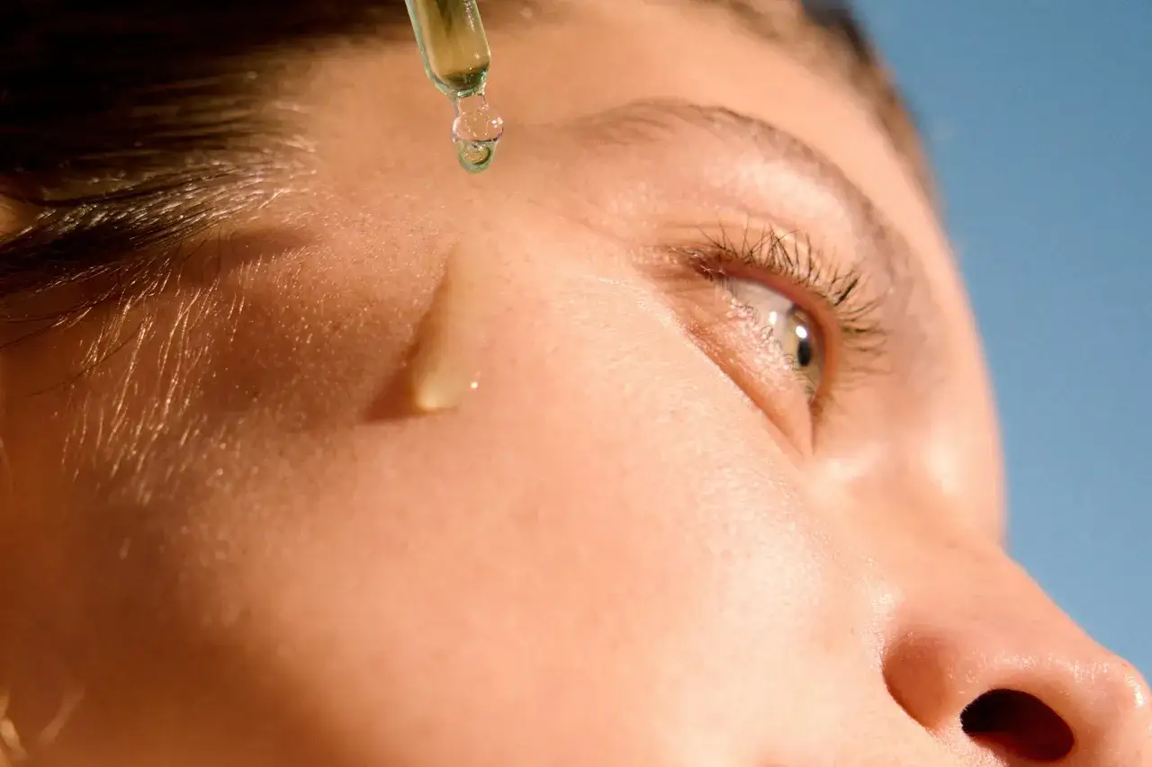 Droppe serum appliceras på huden, en del av hemligheten för hur man får clear skin.
