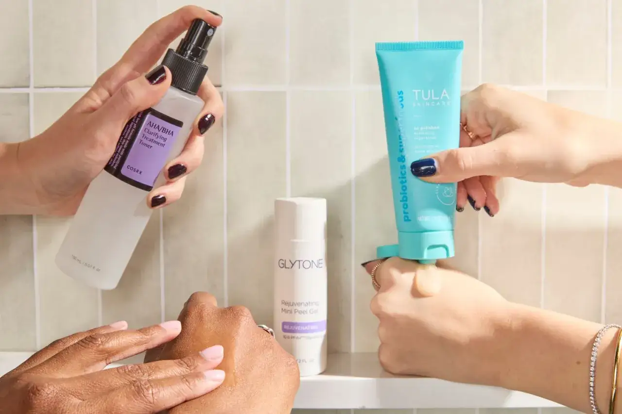 Händer visar hudvårdsprodukter för peeling. En hand håller en toner, en annan en peelinggel och en tredje en exfolierande scrub.