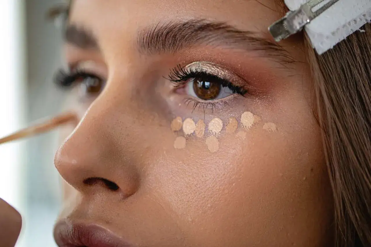 En makeupartist b&ouml;rjar applicera concealer under &ouml;gat f&ouml;r att ljusa upp och d&ouml;lja m&ouml;rka ringar.