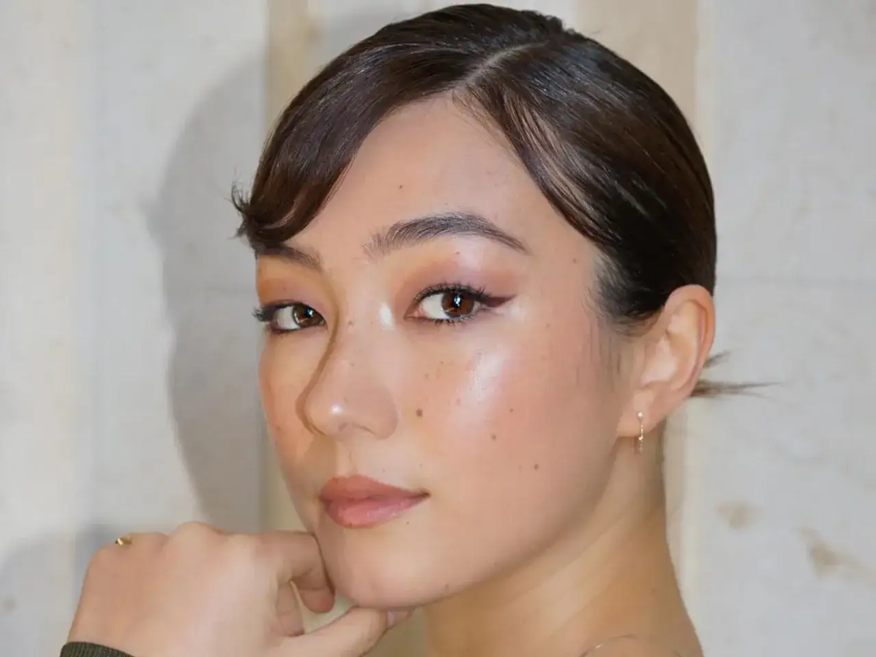 En kvinna med douyin makeup, med gl&ouml;dande hy, mjuk &ouml;gonskugga och en subtil vingad eyeliner.