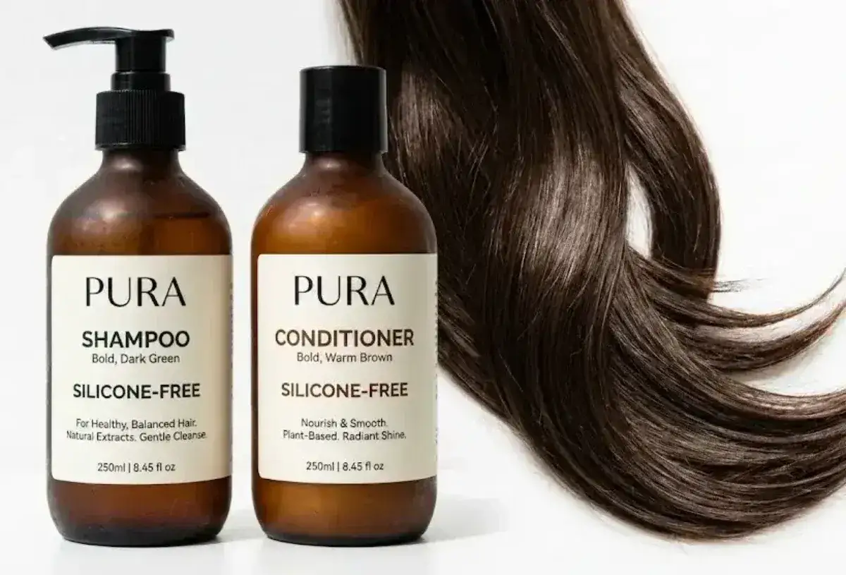 Tv&aring; Pura-flaskor, en f&ouml;r schampo och en f&ouml;r balsam, bredvid en gl&auml;nsande m&ouml;rkbrun h&aring;rsvall. B&aring;da produkterna &auml;r m&auml;rkta 
