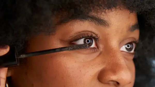 När du vill ta bort vattenfast mascara, använd en mild rengöring. Bilden visar en person som applicerar mascara.